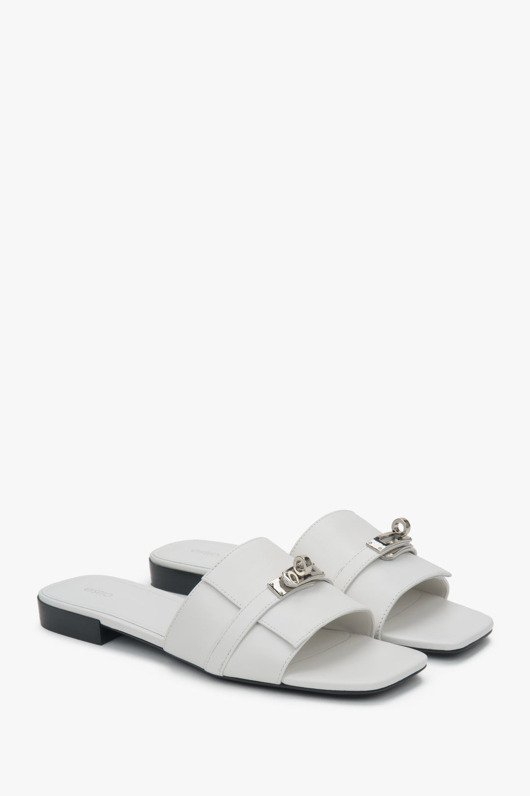 Eleganckie białe klapki damskie Estro, ozdobione subtelną srebrną aplikacją, idealne na lato, z komfortowym płaskim obcasem.