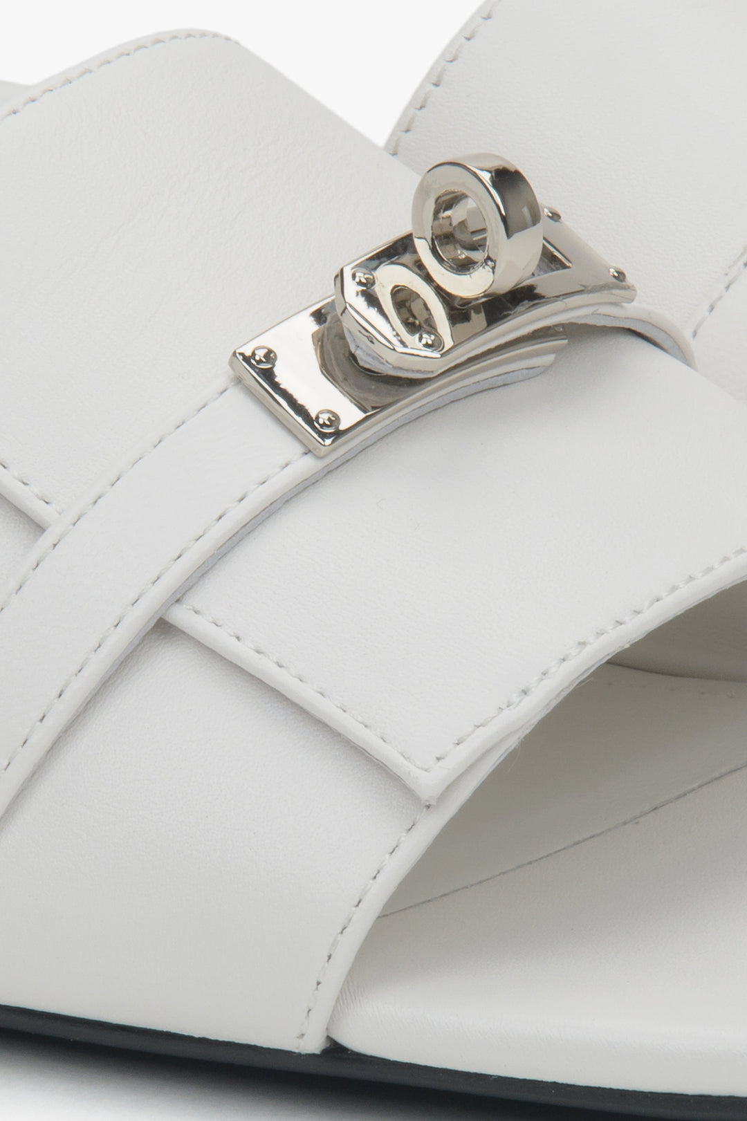 Białe klapki na płaskim obcasie ze srebrną aplikacją od Estro - zbliżenie na detale.