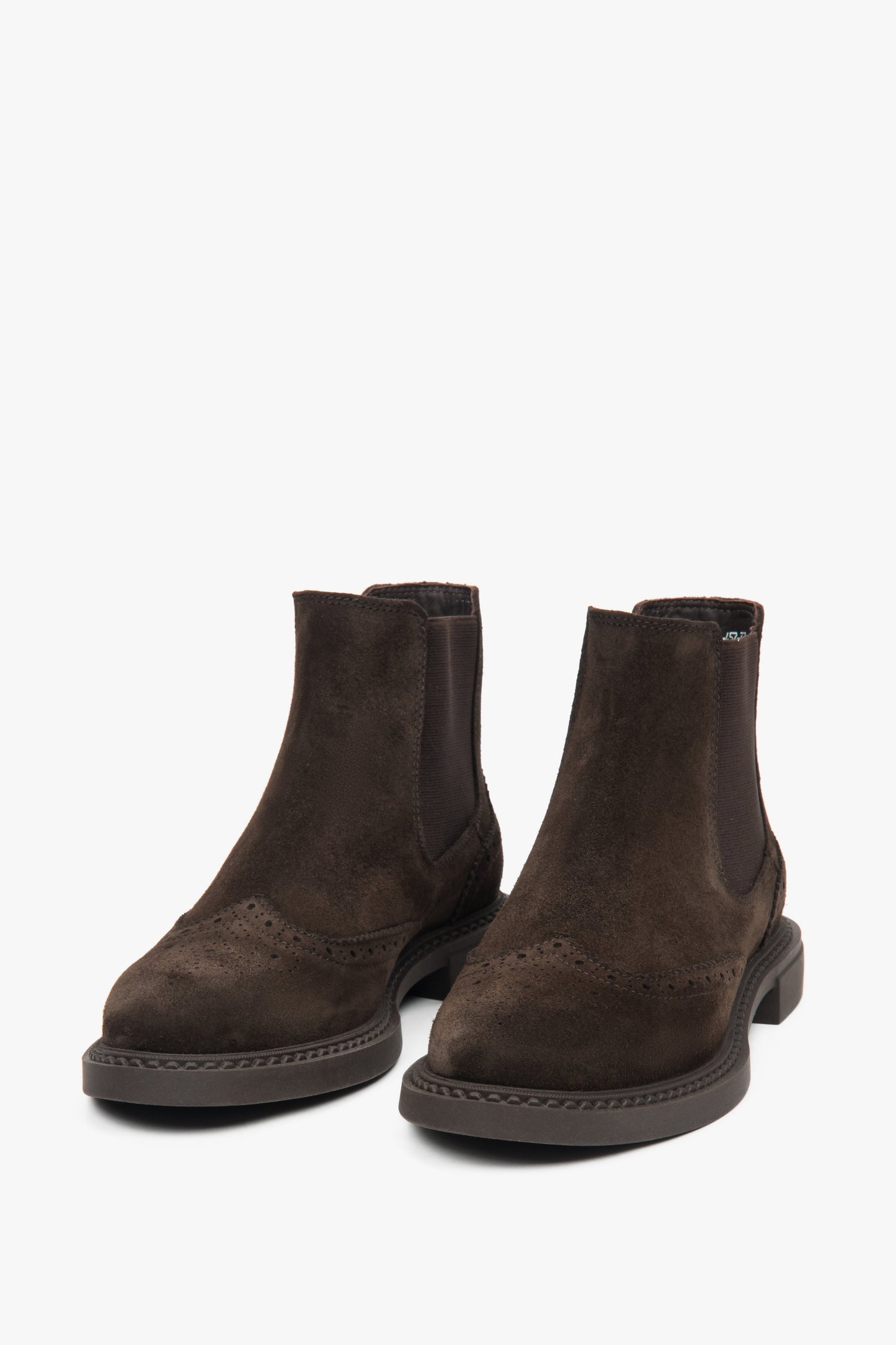 Welurowe sztyblety w kolorze ciemnego brązu, z ozdobną perforacją na nosku i cholewce oraz elastycznymi wstawkami po bokach.