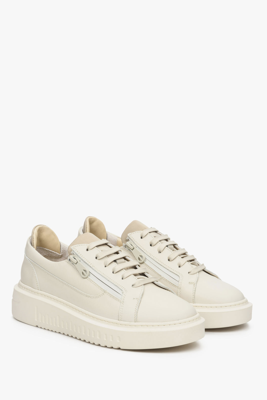 Skórzane, beżowe sneakersy damskie Estro ze sznurowaniem i ozdobnym suwakiem - prezentacja czubka buta i przyszwy bocznej.