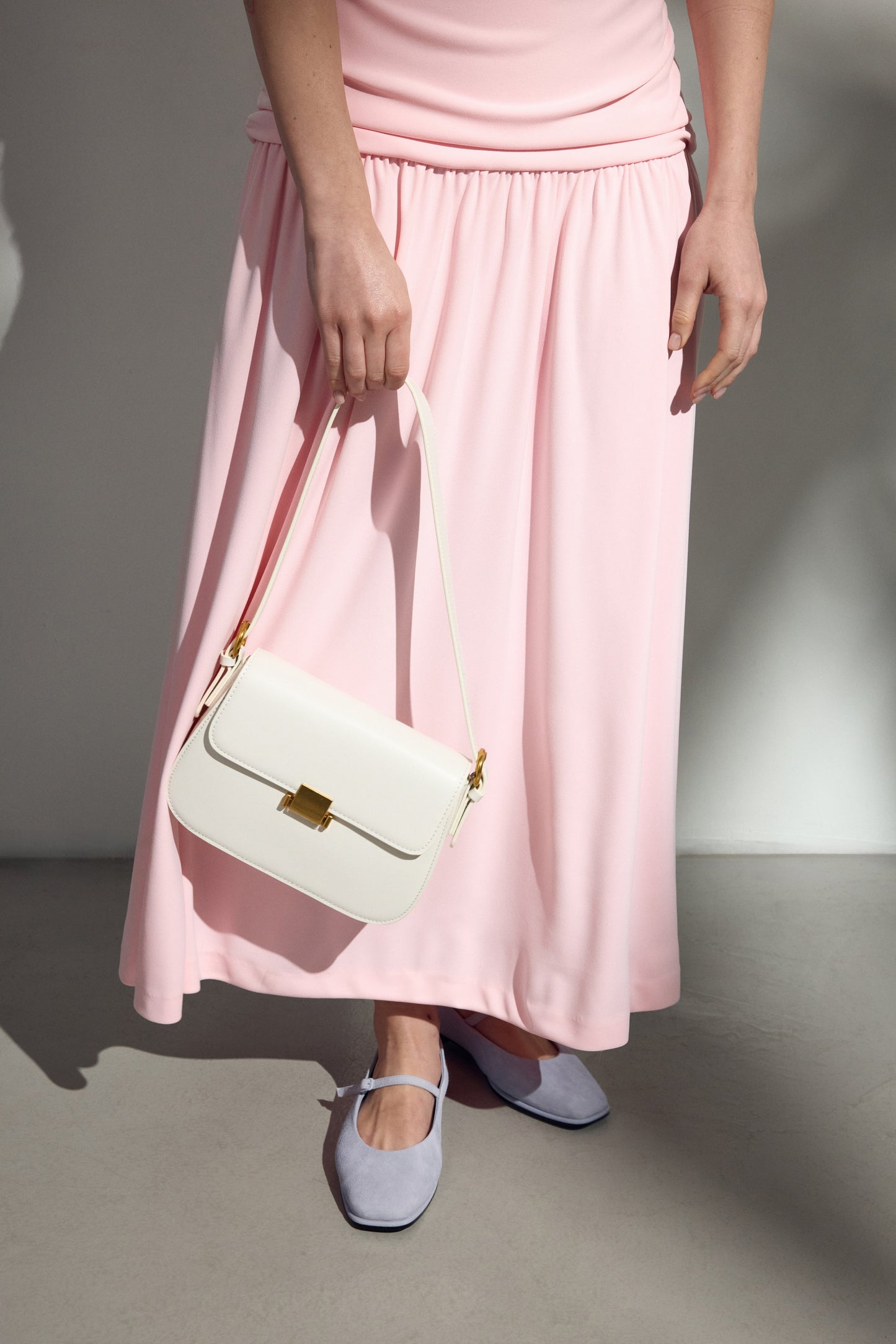 Biała skórzana torebka damska na ramię ze złotymi okuciami.