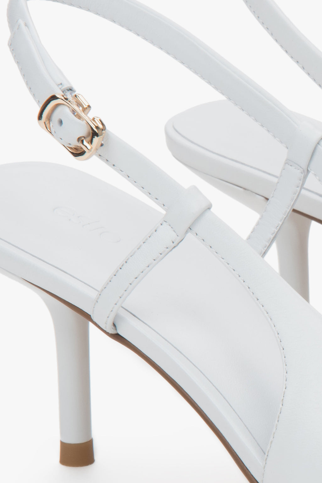 Białe czółenka damskie Estro, z odkrytą piętą, typu slingback, na stabilnej szpilce.