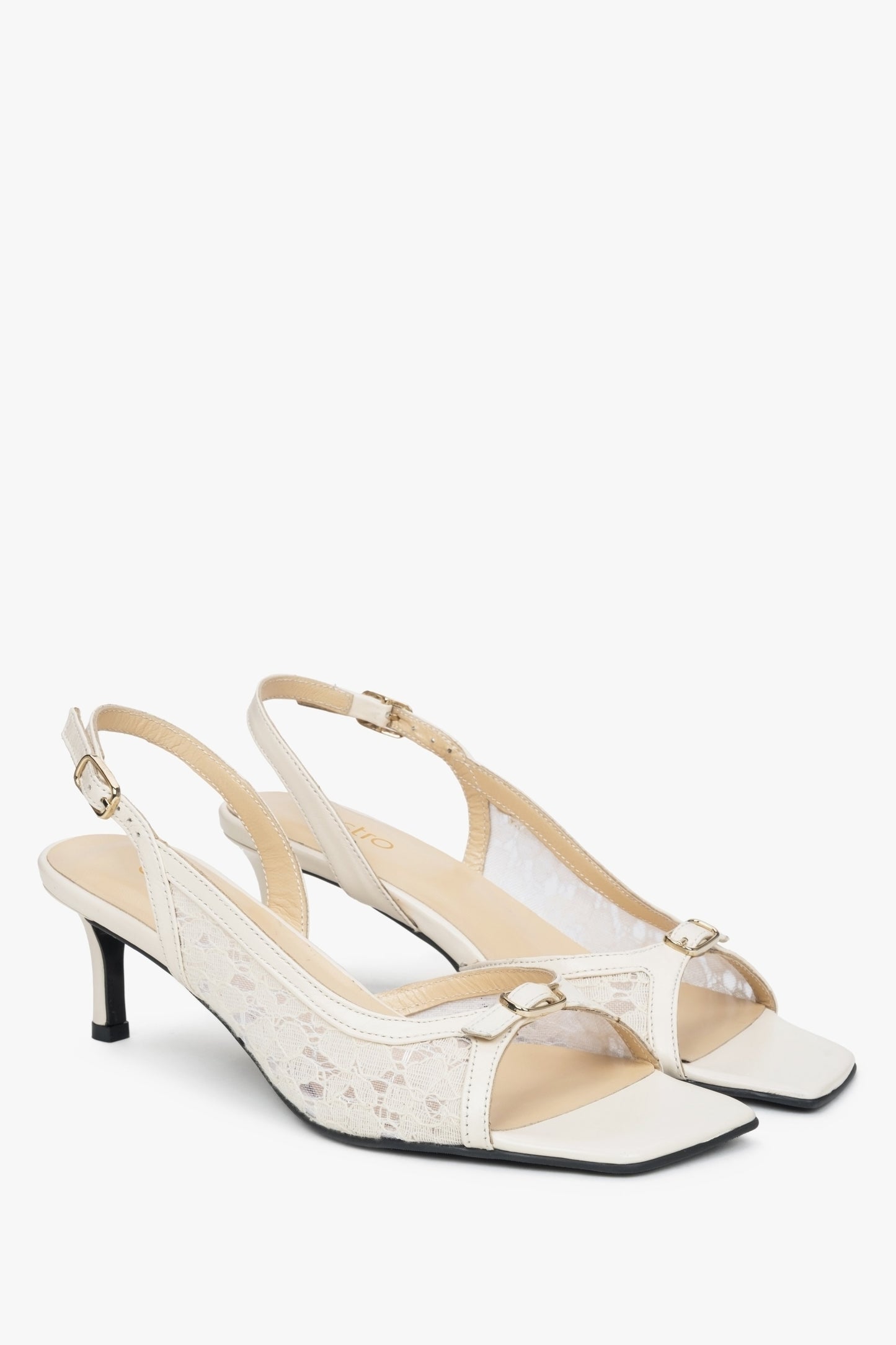 Białe sandałki typu slingback z ozdobną koronką na obcasie.
