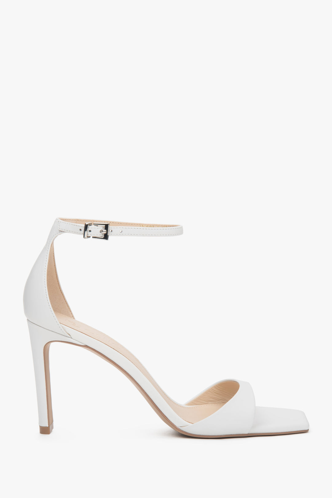 Białe sandałki damskie z lakierowanej skóry naturalnej na stabilnym słupku.