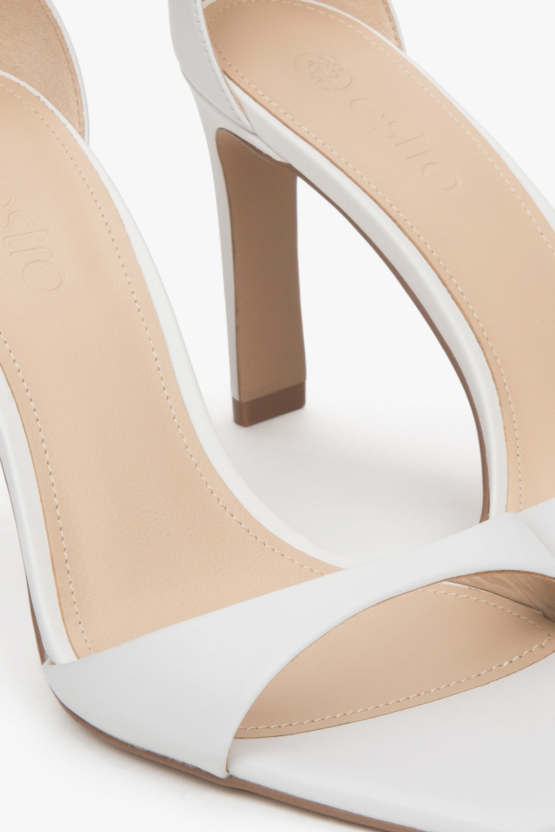 Białe sandałki damskie z lakierowanej skóry naturalnej na stabilnym słupku.