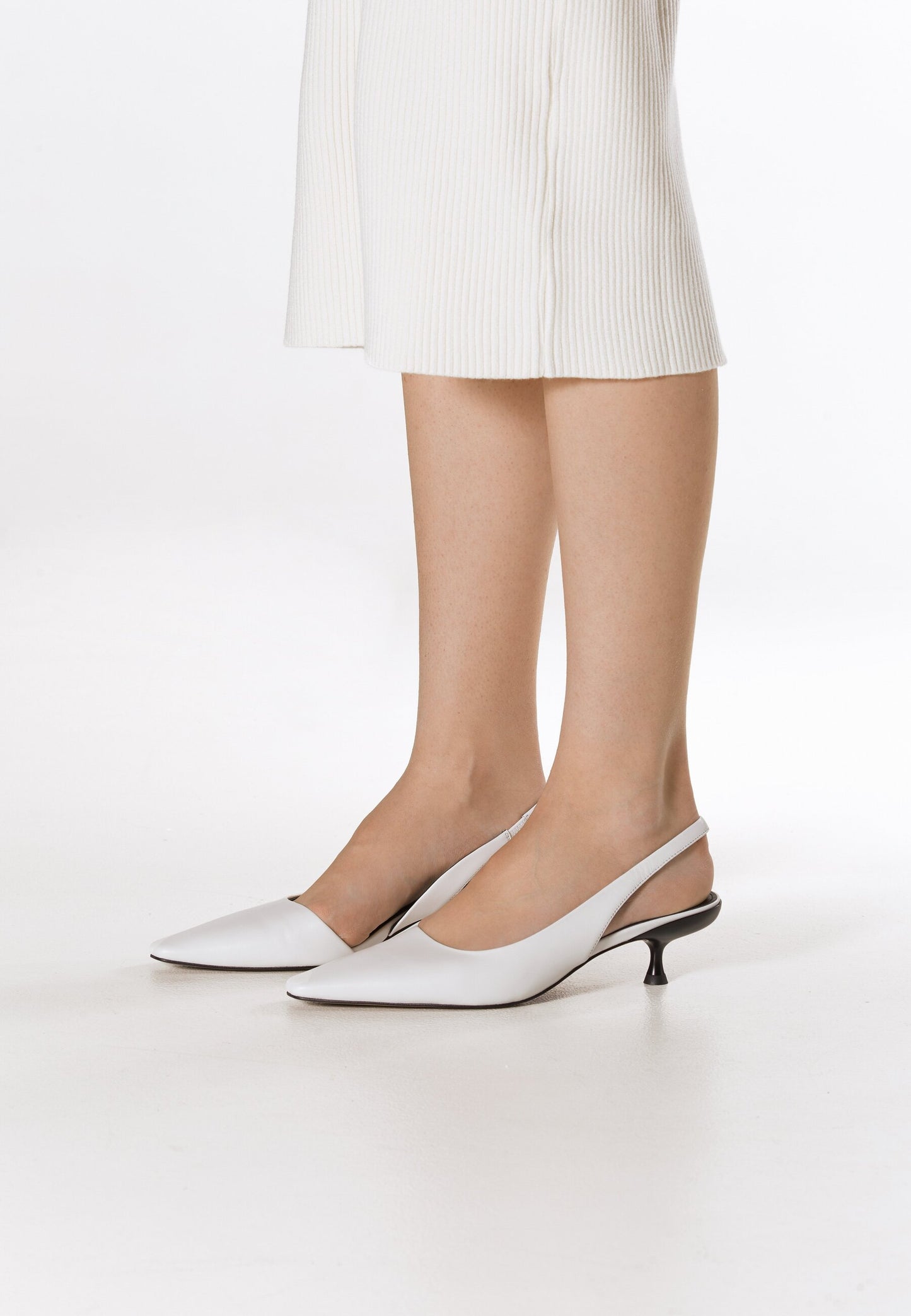 Białe czółenka damskie typu slingback na niskim obcasie, wykonane z naturalnej skóry przez Estro  – prezentacja na nodze.