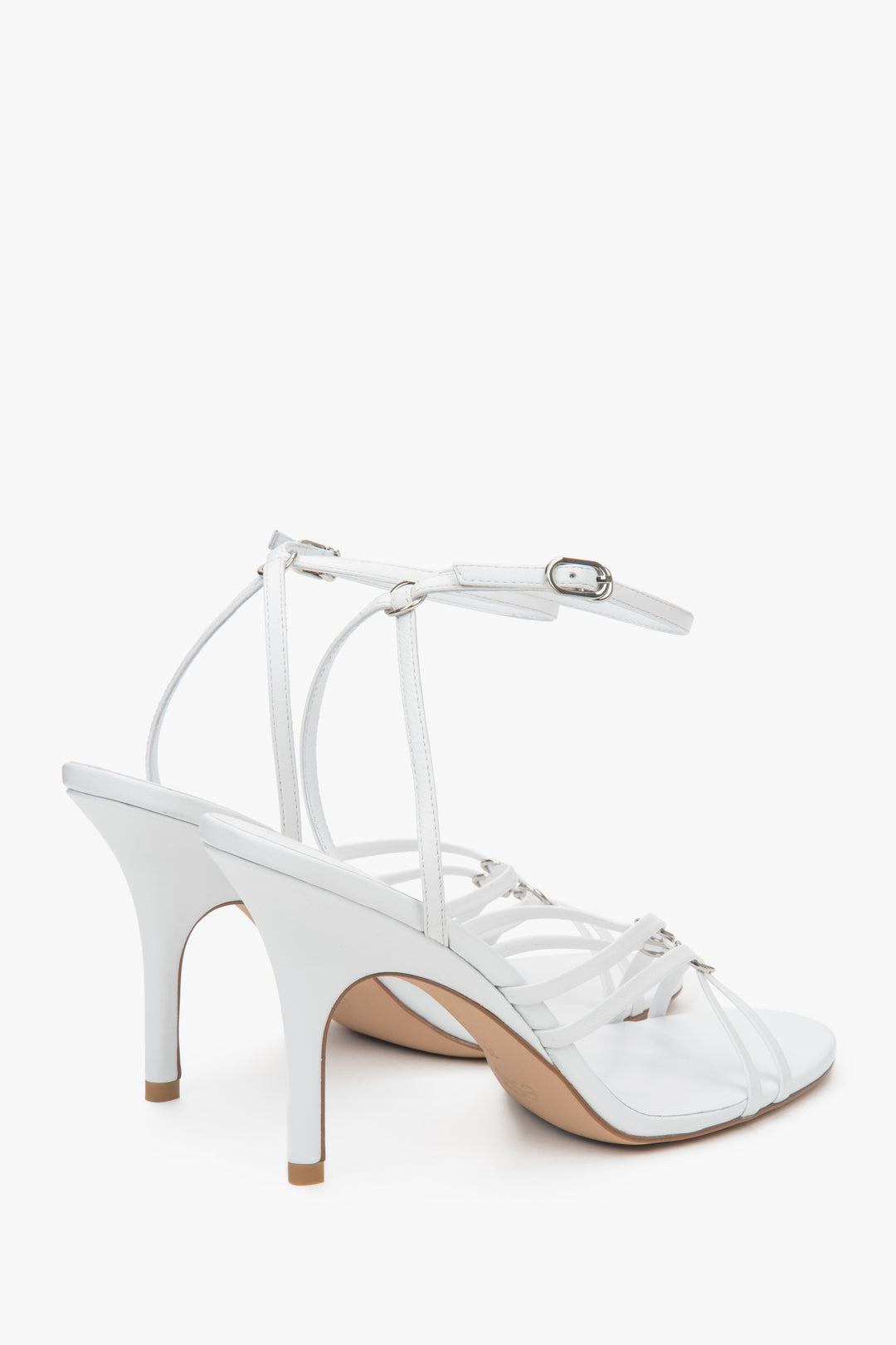 Na szpilce, białe skórzane sandały damskie ze srebrnymi detalami Estro.