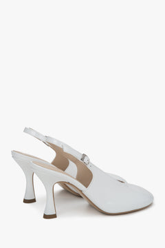 Lakierowane buty damskie typu slingback na obcasie w kolorze białym.