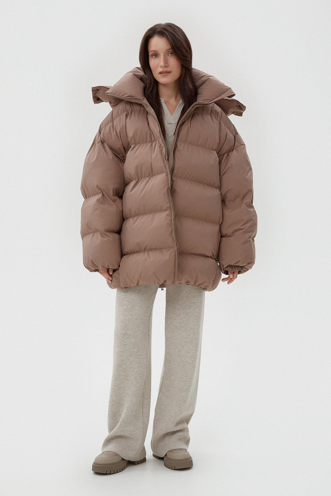 Jasnobrązowa pikowana kurtka damska oversize typu puffer z wysokim kołnierzem.
