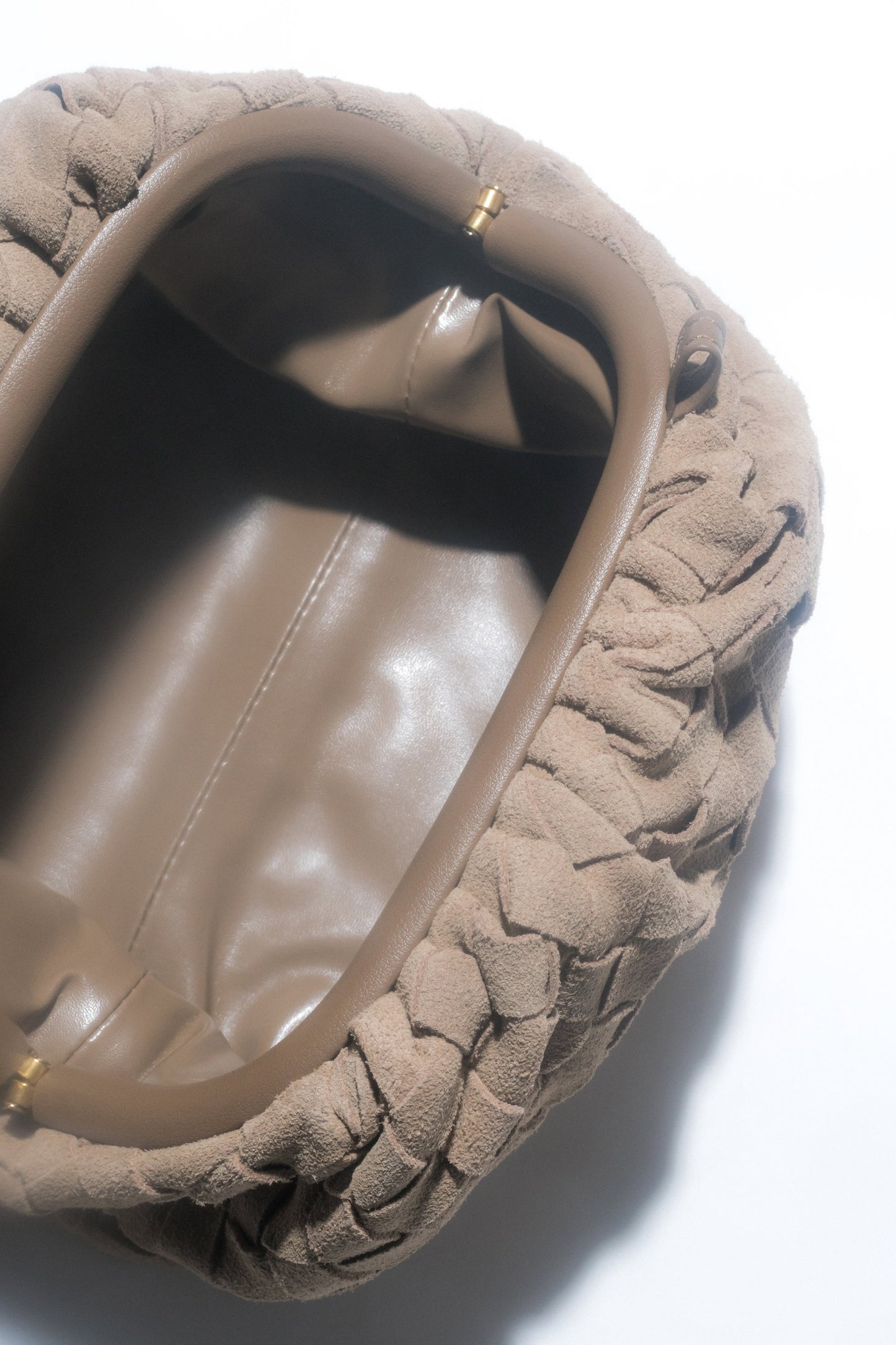 Mała, beżowa torebka damska typu worek z weluru naturalnego.