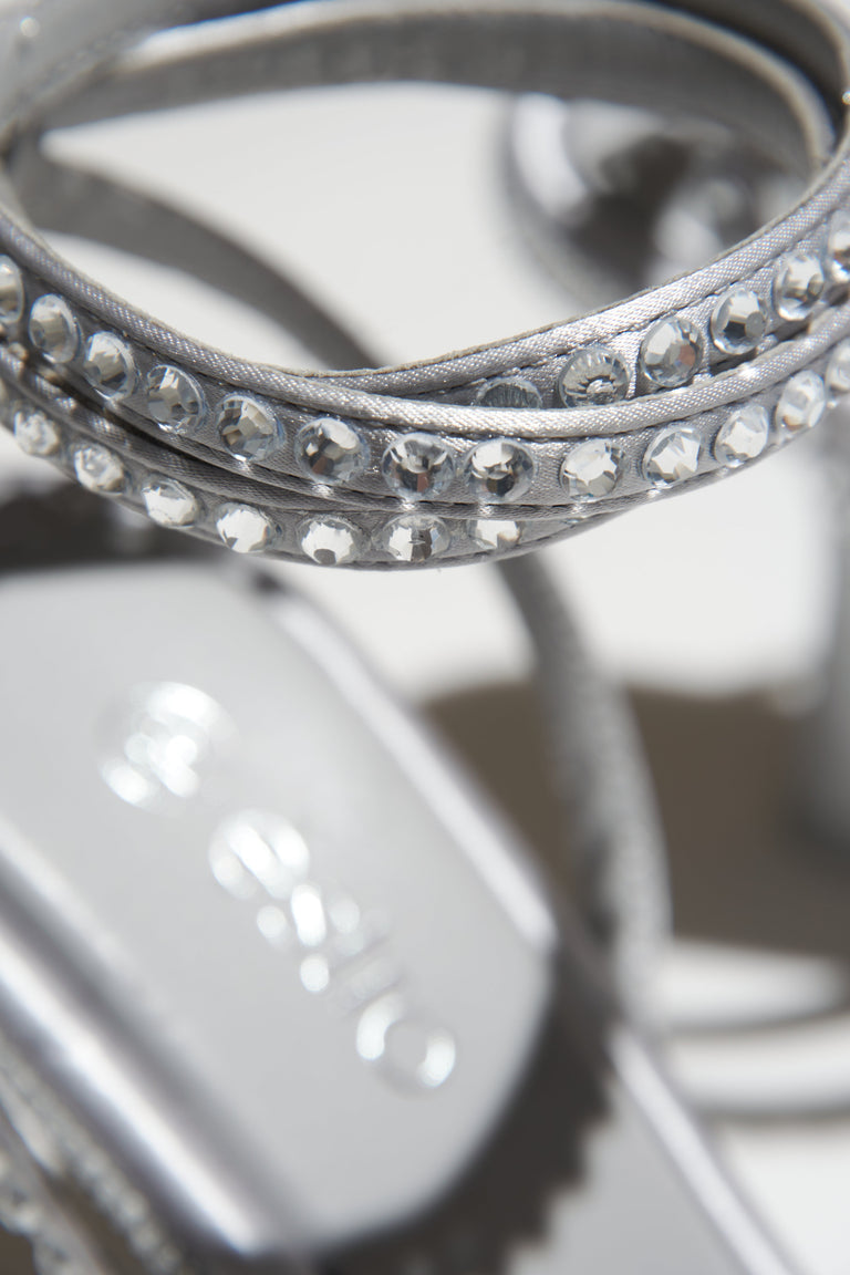 Damskie sandałki na szpilce w kolorze srebrnym wysadzane kryształkami - zbliżenie na zdobienia.