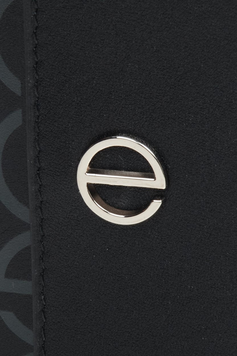 Skórzany portfel damski w kolorze czarnym ze srebrnymi okuciami marki Estro - zbliżenie na emblemat.