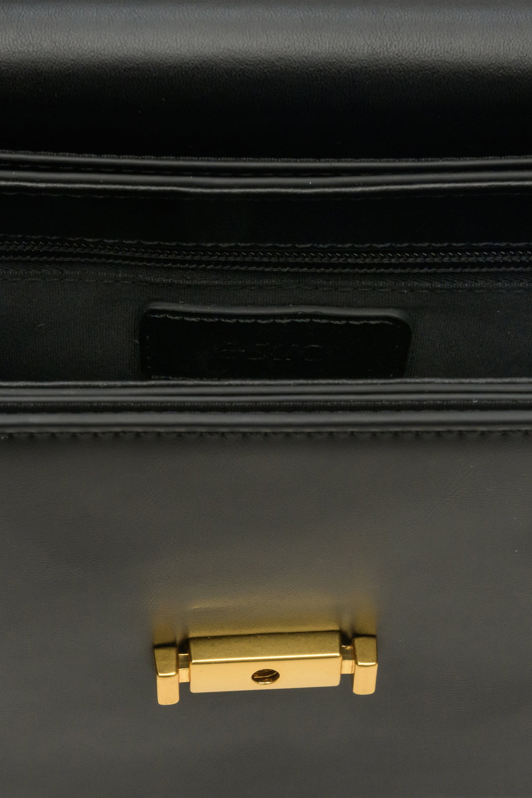 Mała damska torebka ze skóry naturalnej w kolorze czarnym ze złotymi okuciami - zbliżenie na detale.
