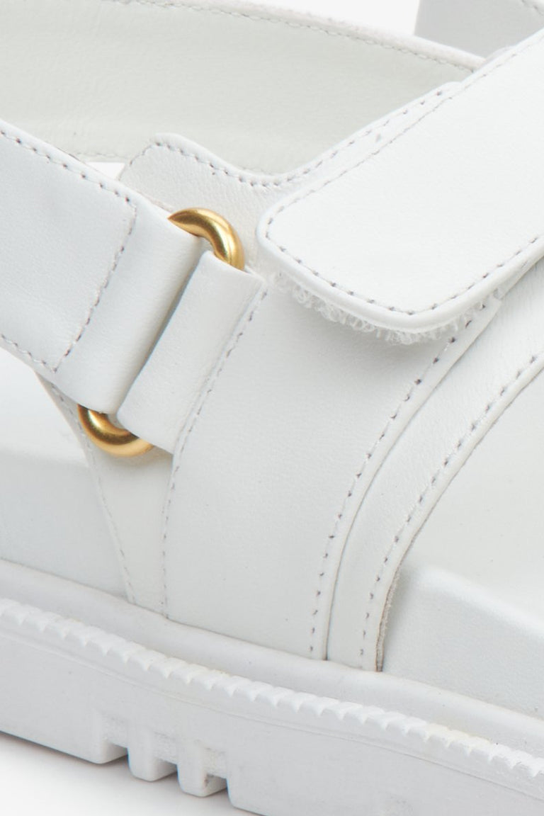 Białe, skórzane sandały damskie na wygodnej podeszwie ze złotymi elementami - zbliżenie na detale.