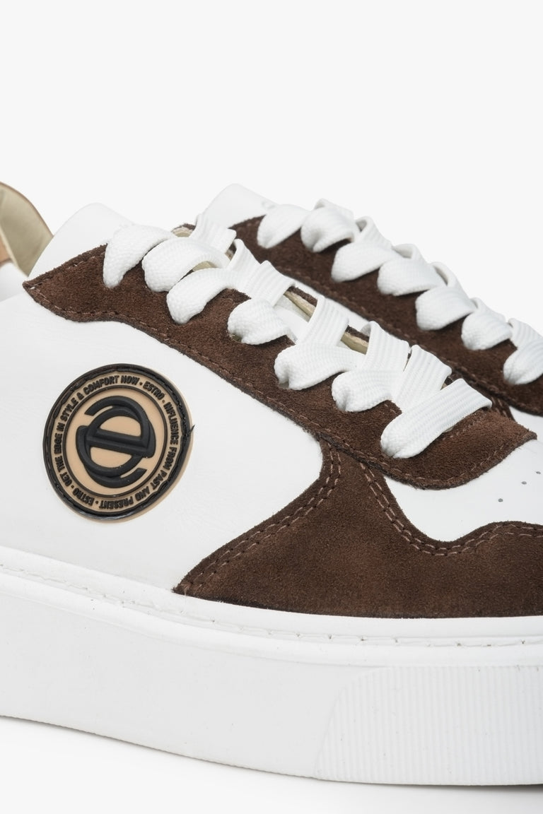 Sneakersy welurowo-skórzane Estro w kolorze biało-brązowym. Zbliżenie na ozdobne logo.