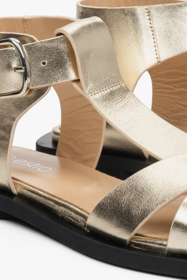Skórzane, złote sandały damskie na płaskiej podeszwie z grubych pasków - zbliżenie na detale.